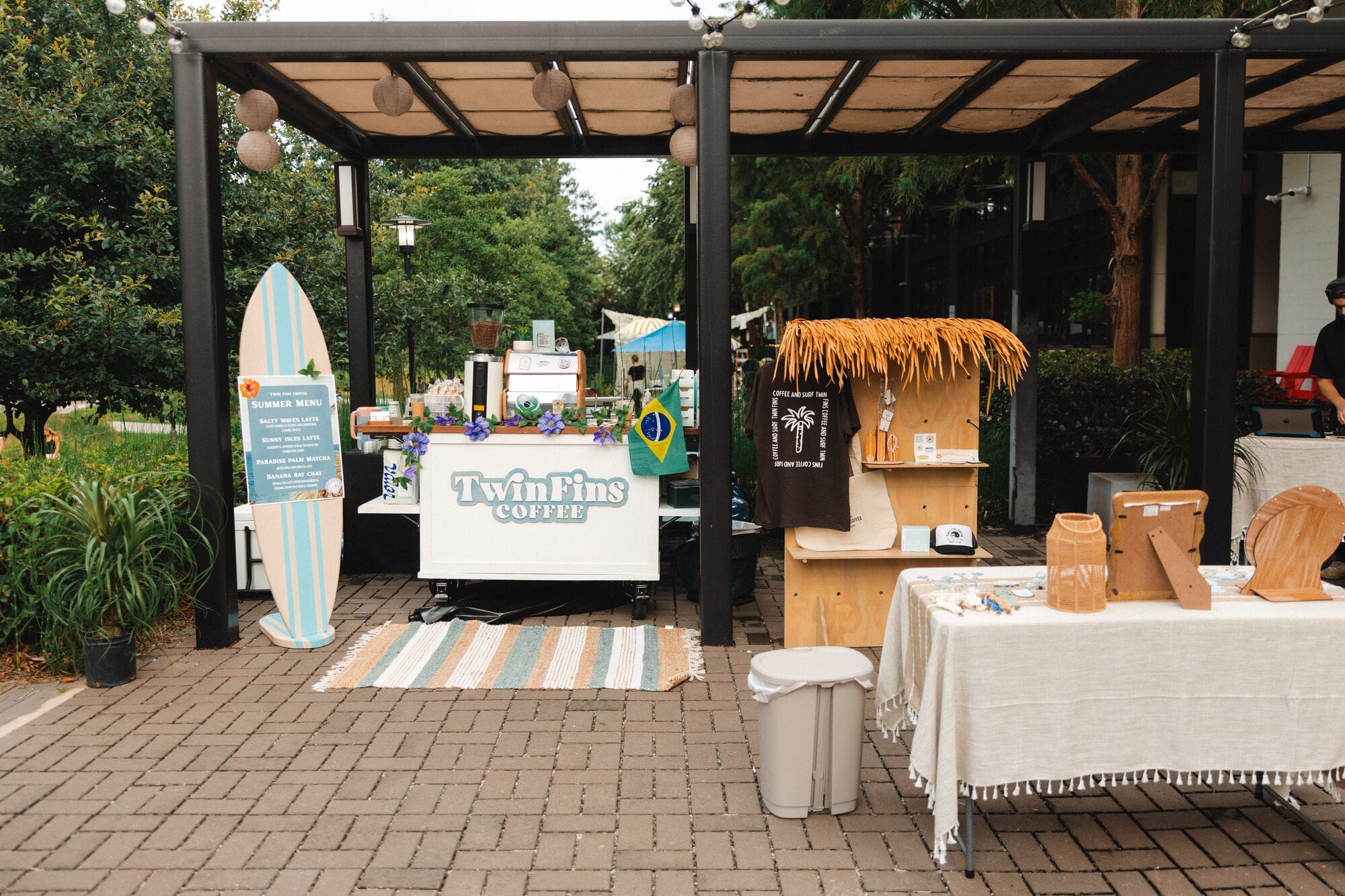 The full Twin Fins setup under a pergola, flanked by a painted surfboard sign