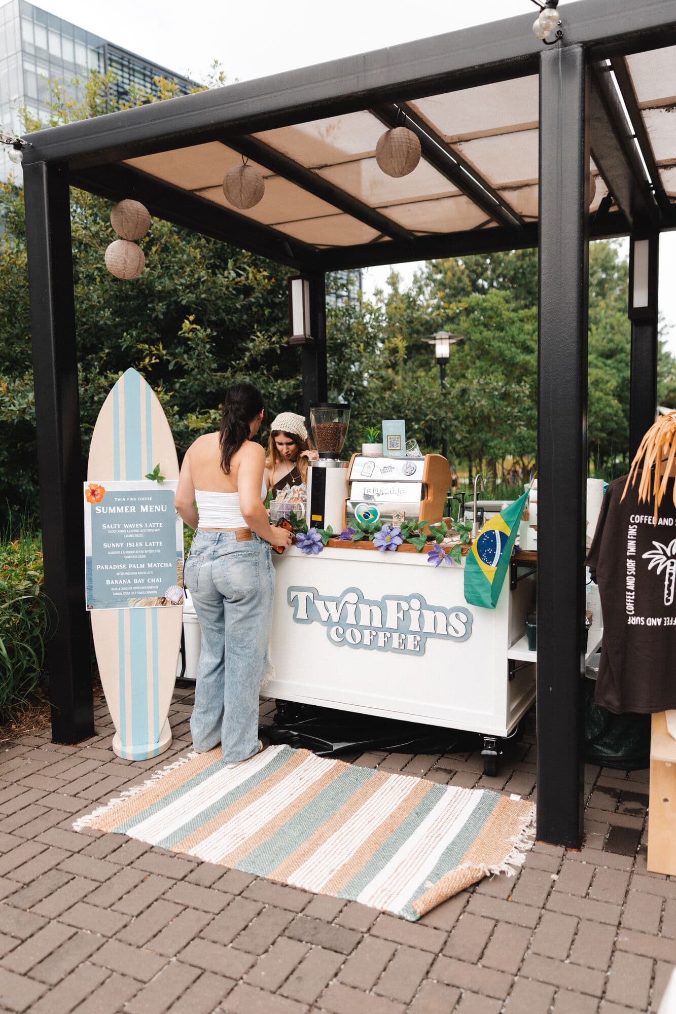 The full Twin Fins cart set up under a pergola, flanked by a painted surfboard sign