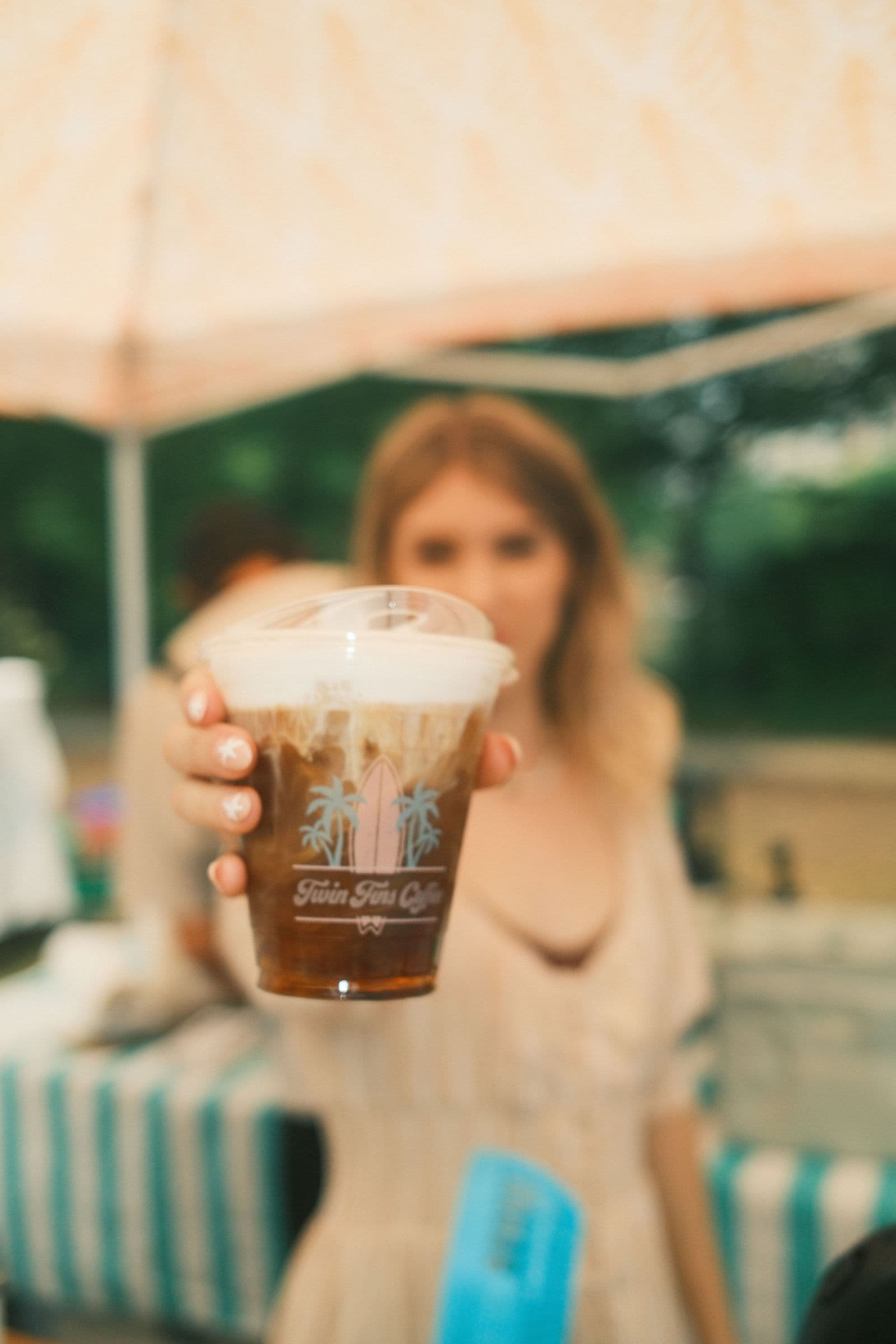 A finished iced Twin Fins latte held out across the bar to a customer