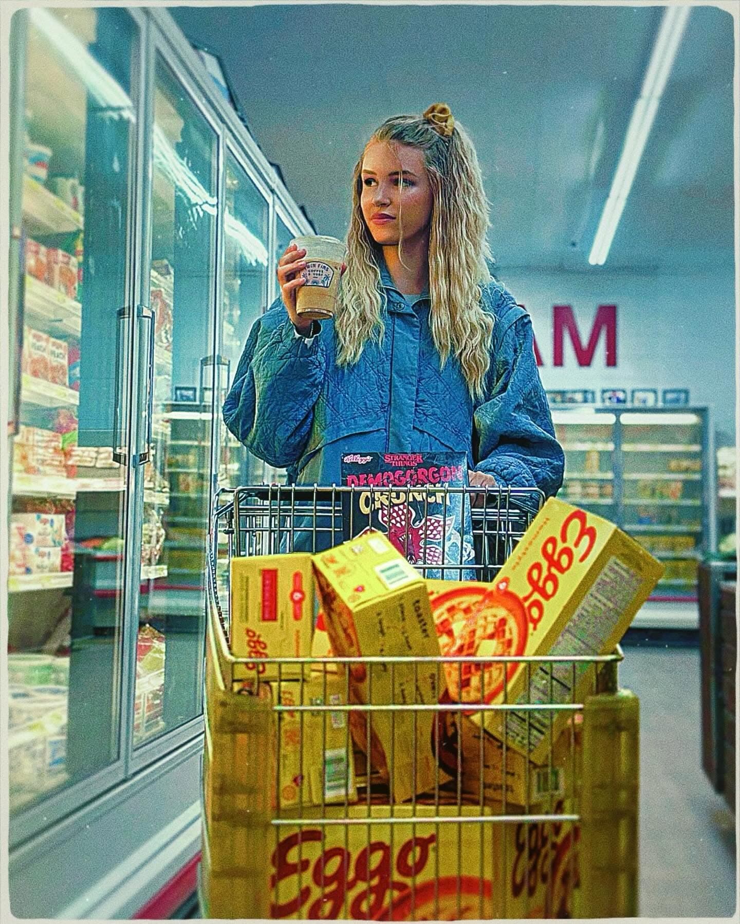 A grocery cart loaded with Eggo boxes and Demogorgon Crunch cereal, Twin Fins cup in hand