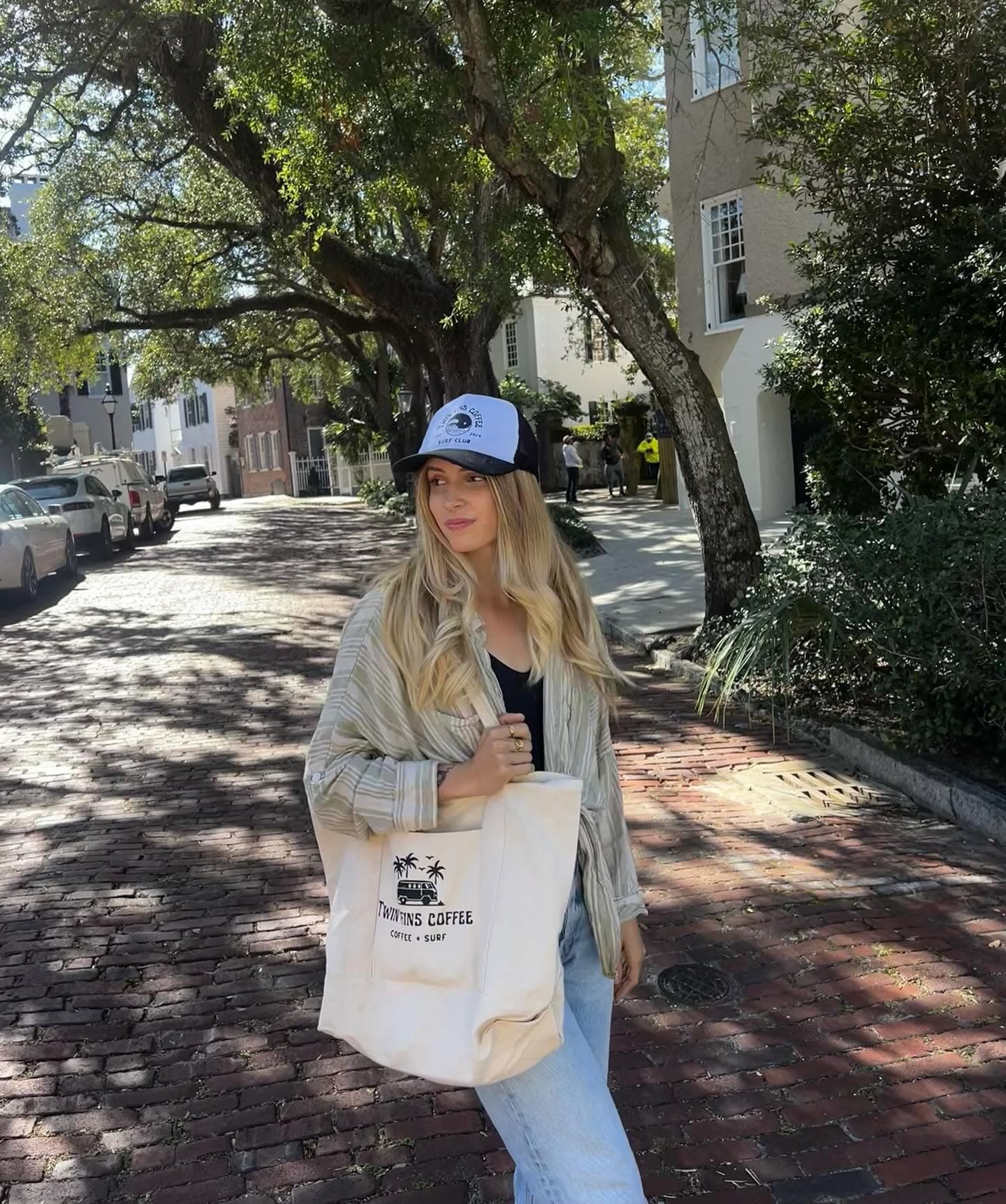 Natalia carrying the Twin Fins Coffee canvas tote down a brick side street